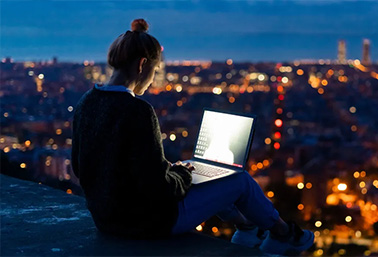 Woman on laptop with city night view